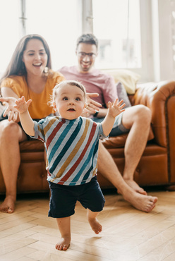 happy mom and dad watching their baby walk