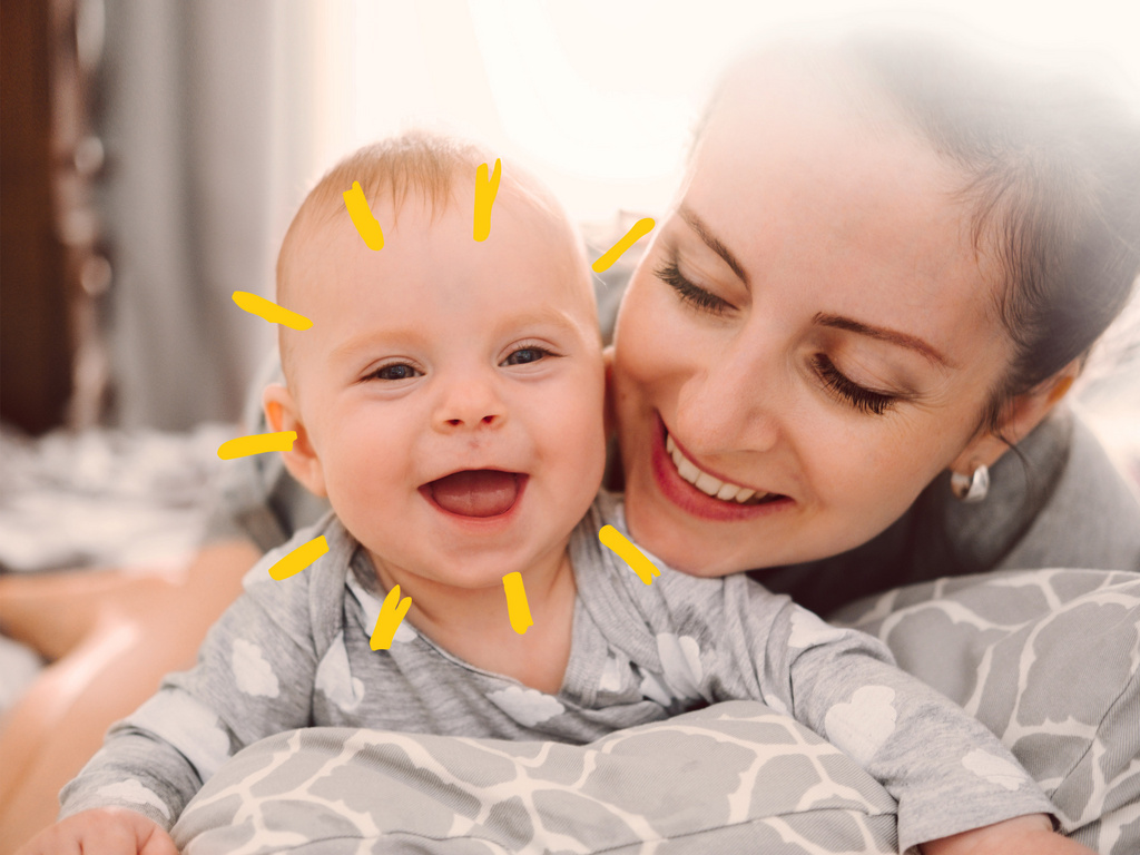 happy smiling mother and baby playing on bed at home