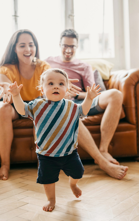 bebe caminando descalzo por su casa y padres felices